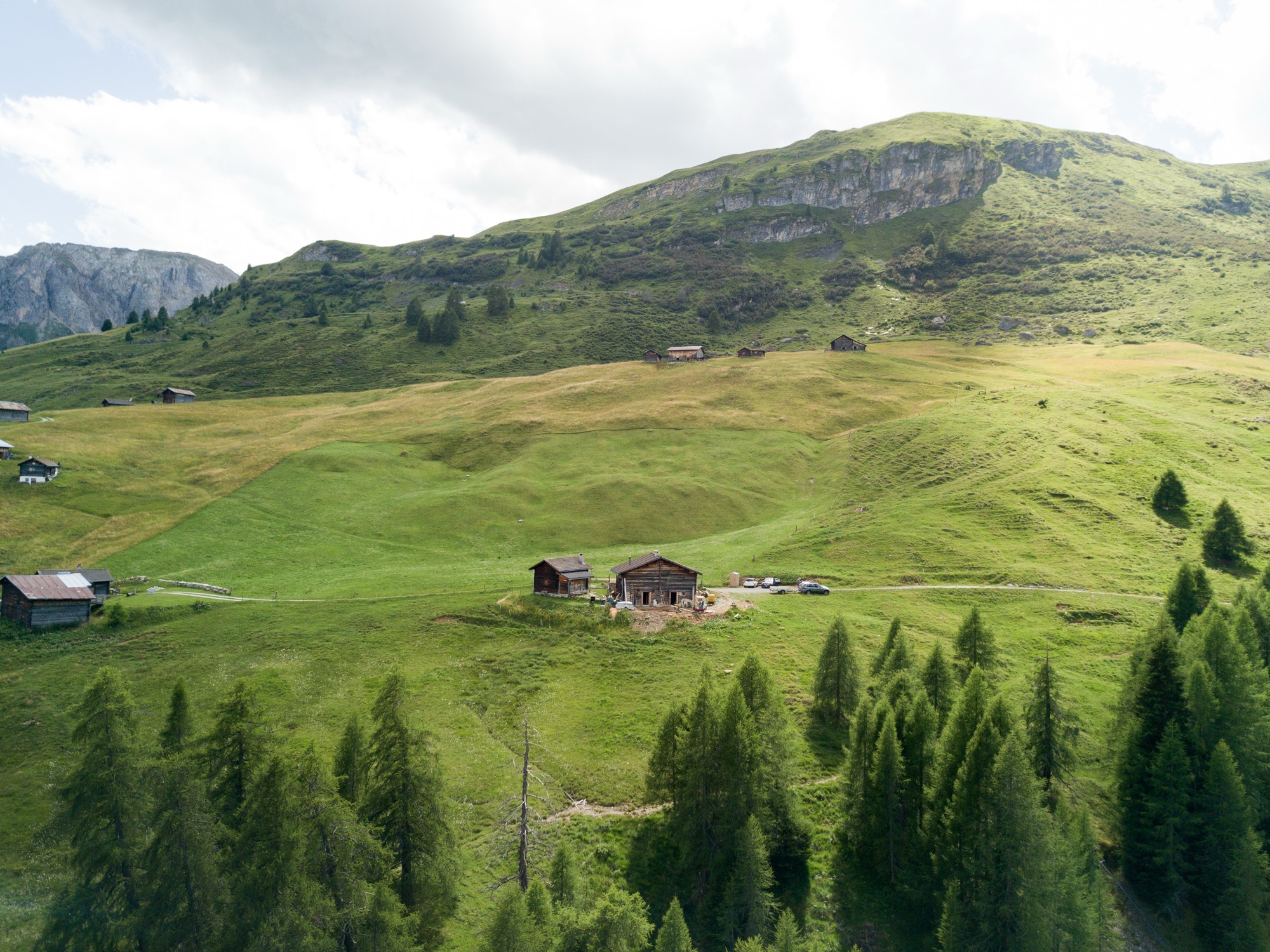Die Hütte in der weiten Alplandschaft mit Wald und Gipfeln