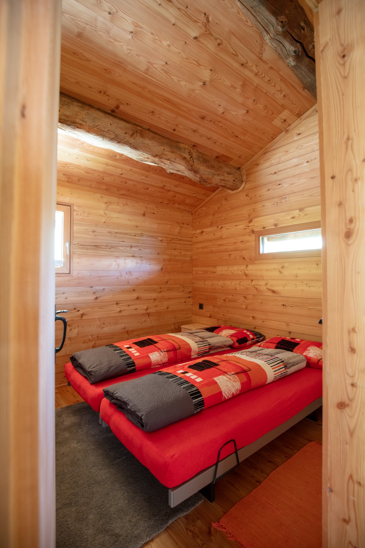 Schlafzimmer mit zwei Einzelbetten und roter Bettwäsche